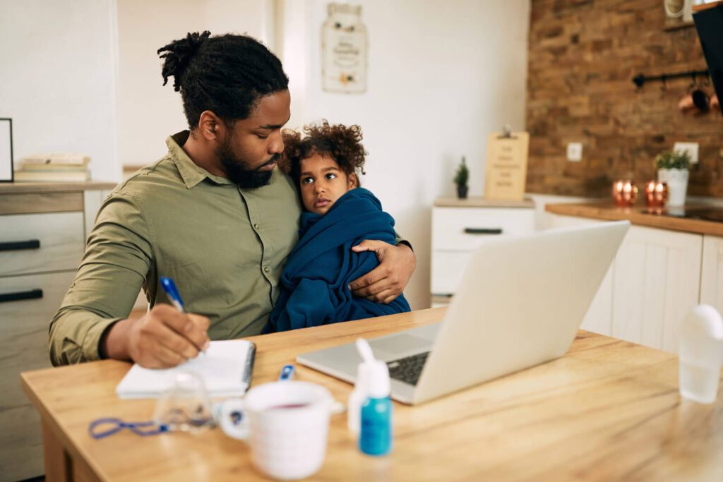 A man working from home with his child on his lap.